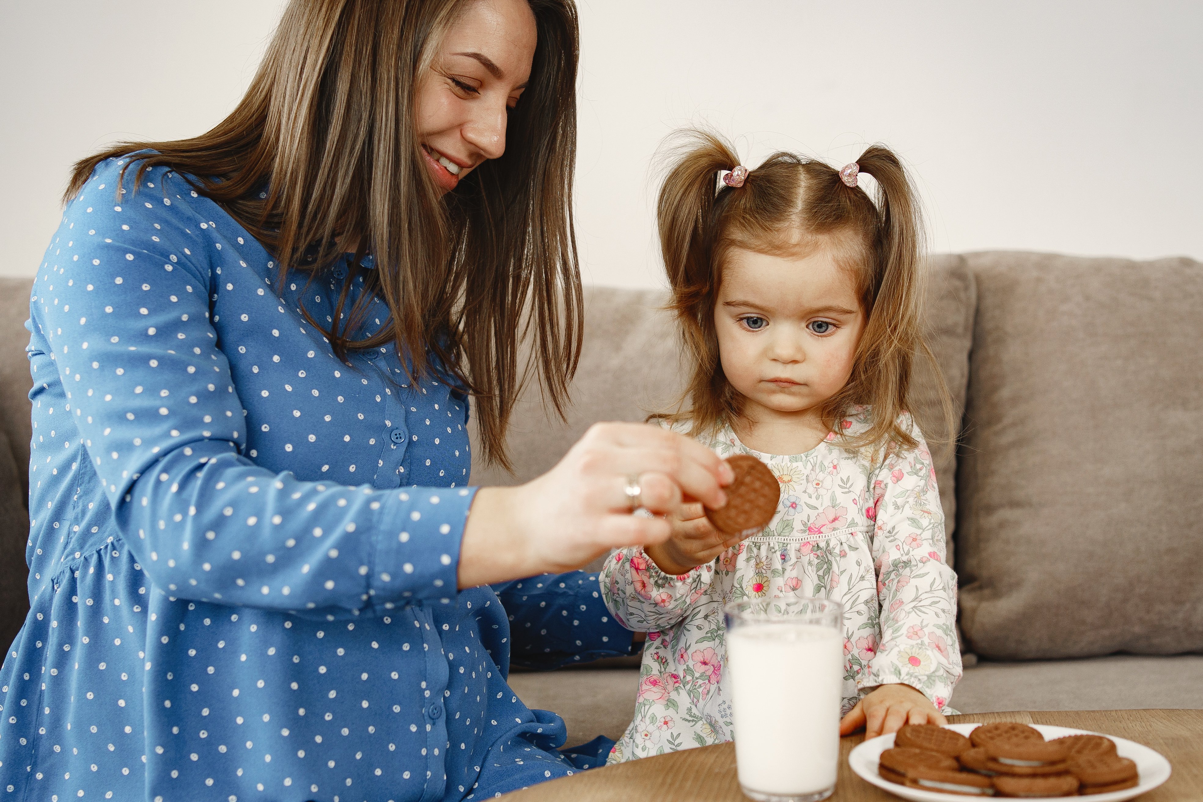 pregnant-mom-in-dress-girl-drinks-milk-mom-and-daughter-enjoy-cookies